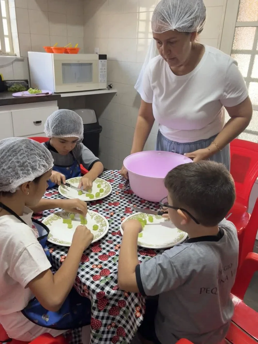 Crianças em atividade de culinária com acompanhamento